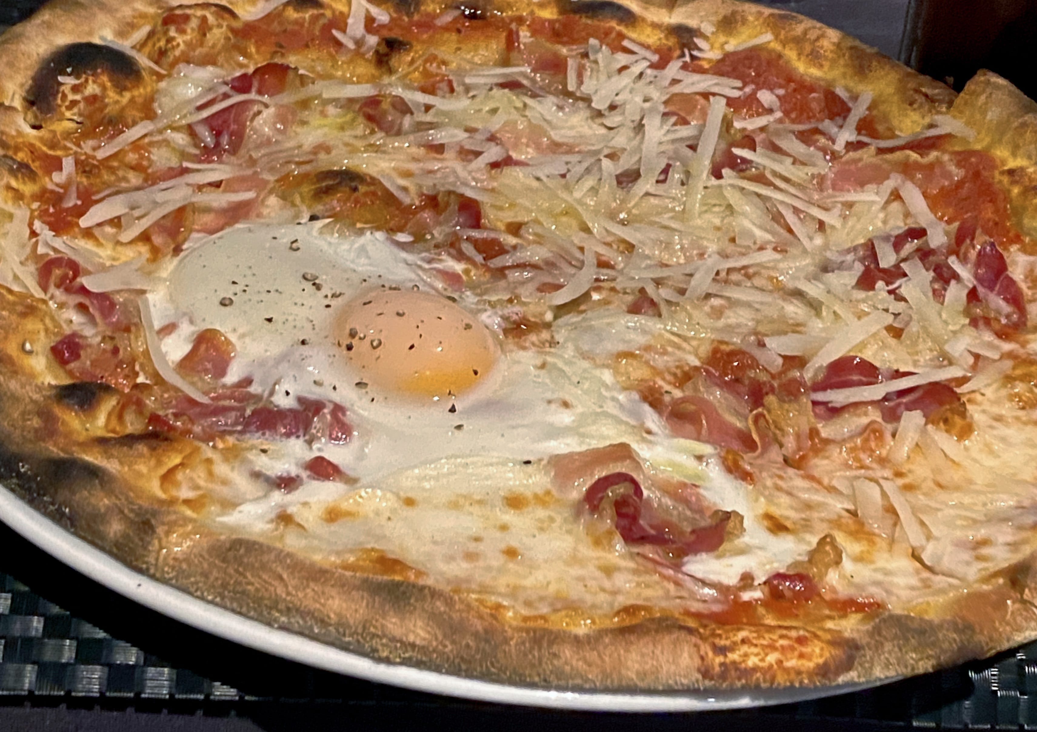 A giant pizza with a fried egg on top of it.